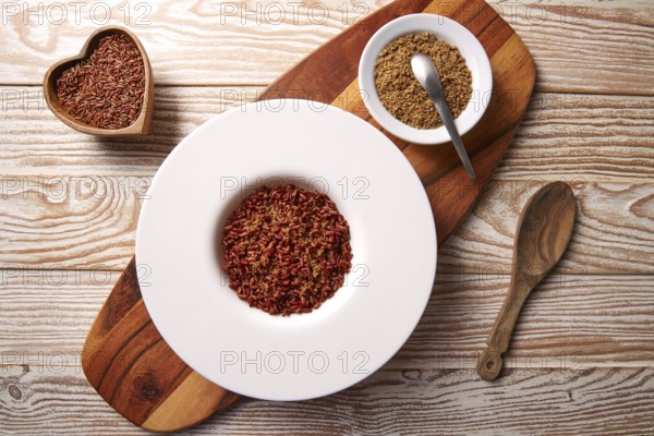 Red wild rice with sesame gomasio seasoning in a white plate over wooden board