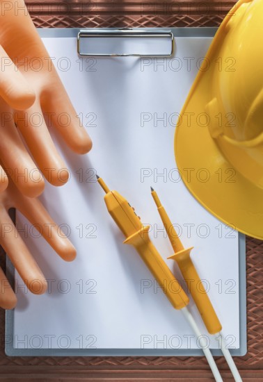 Clipboard paper hard hat insulating gloves electric tester on dielectric cover