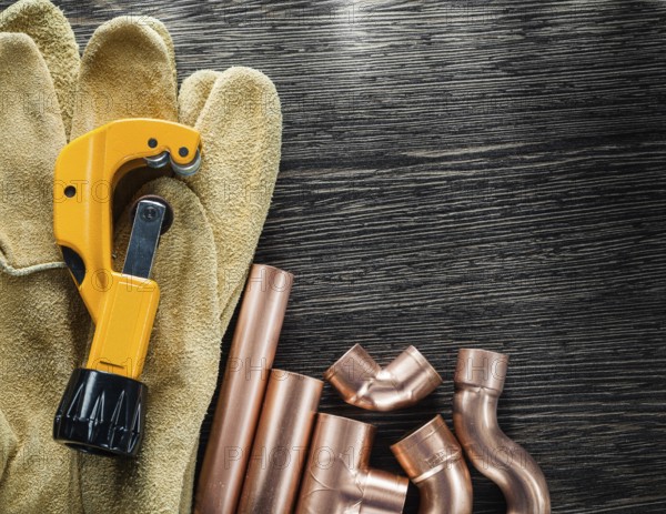 Plumbing water pipe scissors leather protective gloves on wooden board