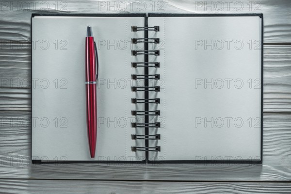 Opened notebook pen on white wooden board