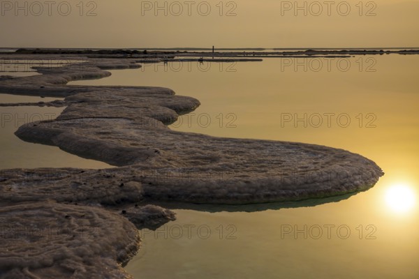 Cloudy winter cool day. Sunrise over the Dead Sea. The foggy sun is reflected in the smooth surface of the water. The concept of active and photo tourism. Israel