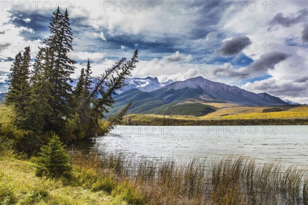 Cloudy Indian summer in the Rockies of Canada. Rocks and lakes under flying clouds. Concept of active and ecological tourism
