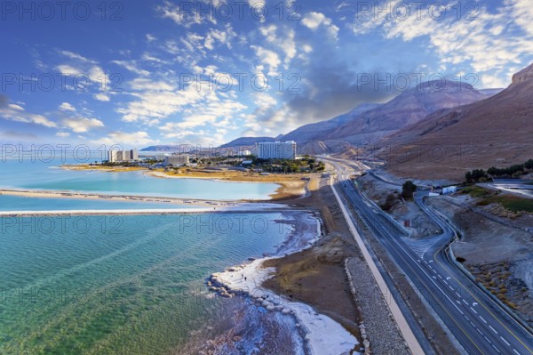 Sunset. Shallowed Dead Sea photographed from a drone. Evaporated salt was deposited along the shore. Asphalt highway runs along the seashore. The winter in Dead Sea