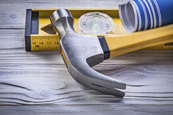 Claw hammer blue rolled engineering drawings construction level on wooden board