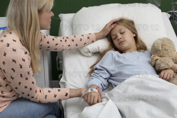 A mother comforts her sick daughter in a hospital bed, showing deep love and support during this tough time