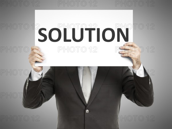 A business man holding a paper in front of his face with the text solution