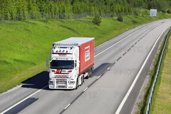 White and red Scania R560 semi trailer truck Toten Transport Oy transports goods along motorway with slow traffic. Salo, Finland. June 12, 2020