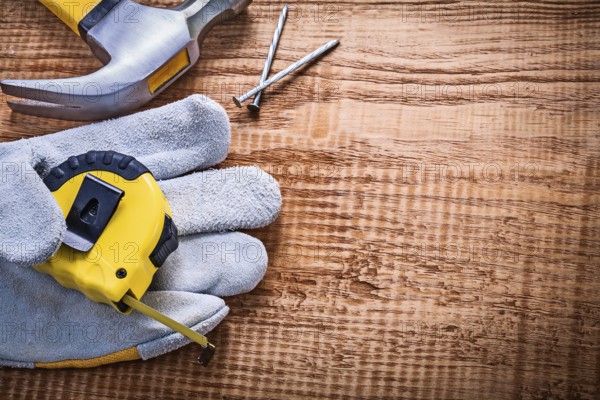 Yellow roulette in protective glove hammer nails on vintage wooden board construction concept