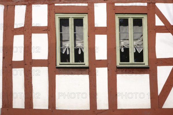 The beam construction and timber frame of a half-timbered house with two narrow wooden windows