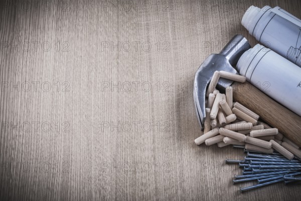 Blueprints hammer dowels nails on wooden board construction concept