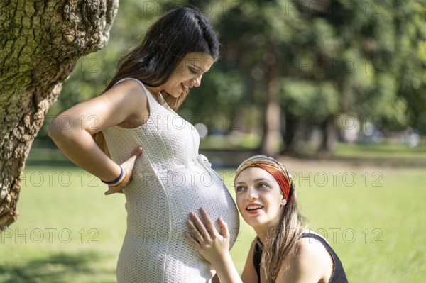 Latin woman listening to his beautiful pregnant girlfriend's tummy