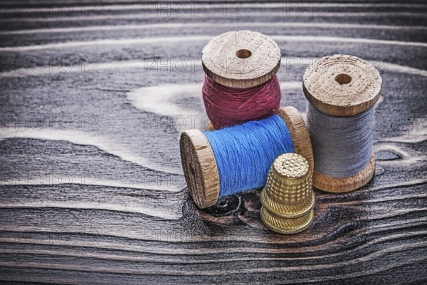 Vintage reels of thread thimbles on wooden board handicraft concept