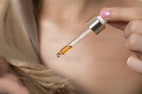 A closeup view of a dropper filled with luxurious hair oil, emphasizing its nourishing and hydrating benefits