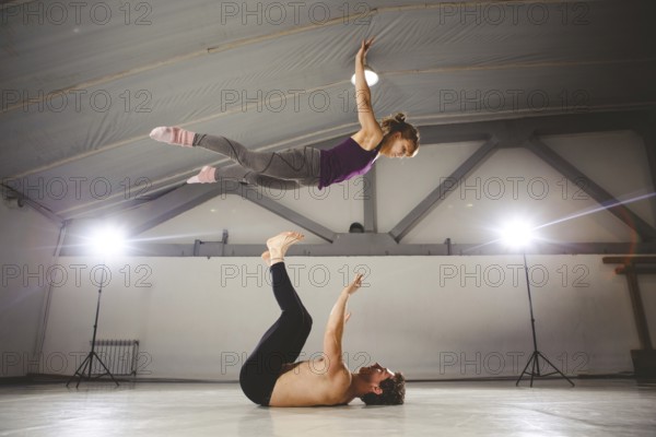 The theme of Acroyoga and Yoga Poses. Acroyogis practicing. with studio Backlight. the Base man tosses the Pops woman Flyer in flight up. Position Acrobatic flying