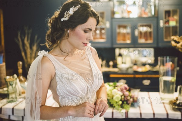 Bride in beautiful dress standing indoors interior at home. Trendy wedding style shot. Wedding makeup and hairstyle. Beautiful Bride in the morning. Emotional bride in her wedding day