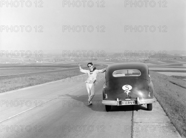 Vaction in Italy in the 1951. A man at his car during a car vacation trip in Italy. He has stopped along a road and waves at the photographer. Conard ref 1666