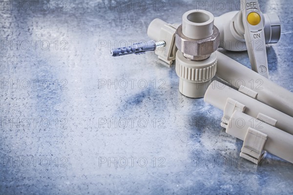 Plastic water pipe valve clamps connectors on metallic background construction concept