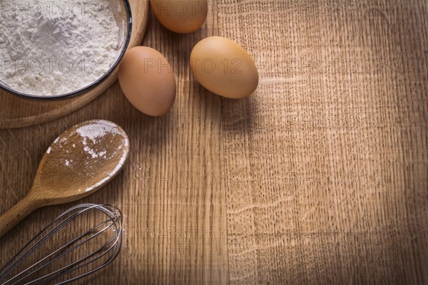 Organized copyspace eggs flour in bowl spoon corolla on wooden board food and drink concept