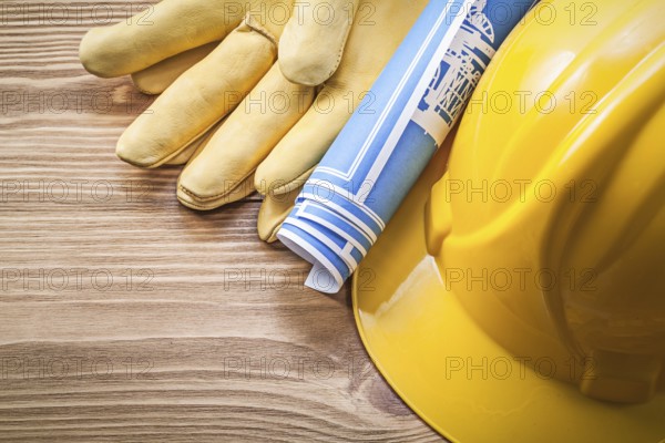 Blue engineering drawing building helmet safety gloves on wooden board construction concept