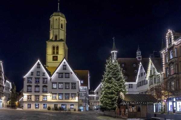 Night photo of historic buildings around the market square with Christmas tree and Christmas lights around the roofs of the buildings and in the background the steeple of the parish church of St Martin, Biberach an der Riß, Upper Swabia, Baden-Württemberg, Germany, Europe