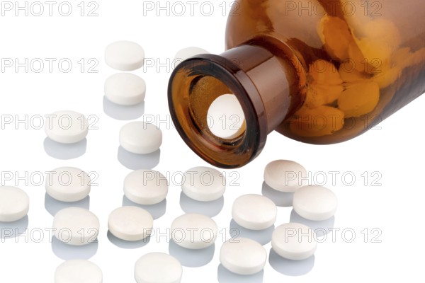 Many tablets with a glass container. Symbolic photo for addiction and costs in medicine and medication. Austria
