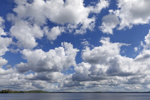 Blue sky with white to grey clouds over the Plöner See in Schleswig-Holstein. These are cumulus clouds. Dramatic sky with blue sky and many white or grey cumulus clouds over water