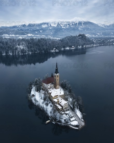 Aerial shot of lake Bled on a calm winter morning with snow