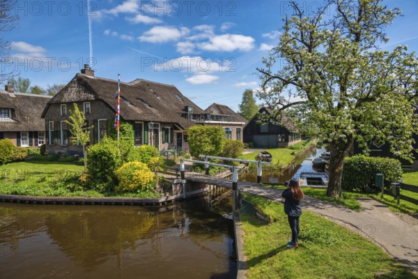 Giethoorn Netherlands, city skyline at canal and traditional house in Giethoorn village with tourist woman
