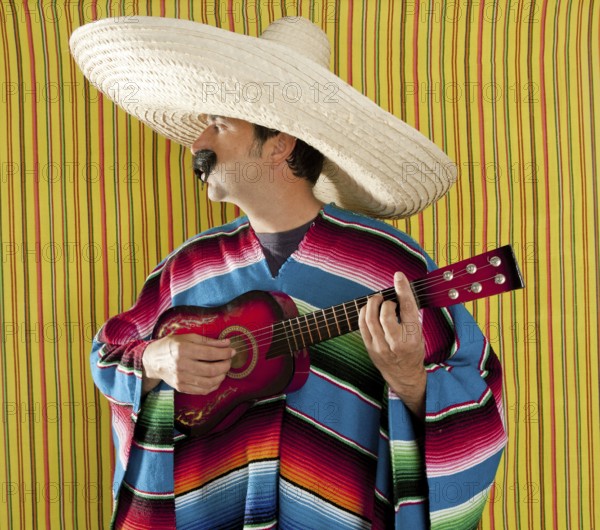 Mexican man serape poncho sombrero playing guitar typical Mexico