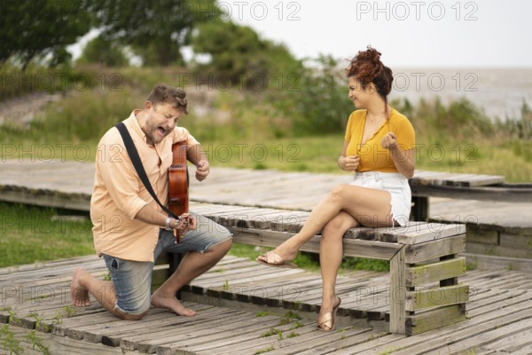 Woman dancing while sitting while her boyfriend plays guitar and sings