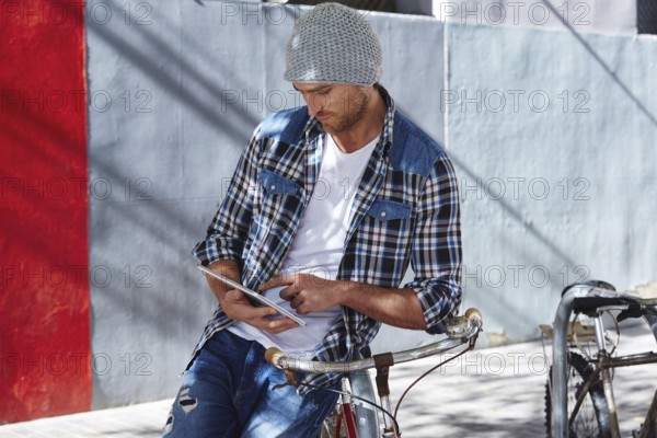 Young man using tablet pc touch in a bicycle casual clothing outdoor