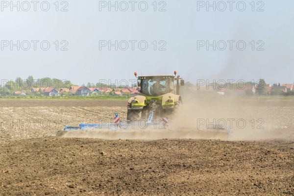Farmer in tractor preparing land seedbed cultivator. Agriculture tractor landscape