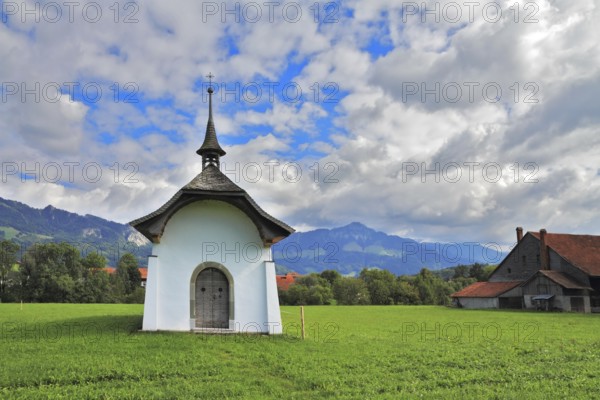 Small rural chapel on a green meadow. Picturesque forged door decorated rows of round rivets. A warm day in Southern France
