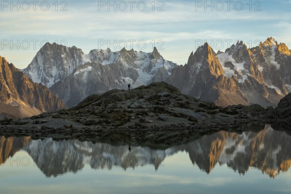 Silhouette of Hiker, Mountains and Reflection in Lac Blanc Lake at Sunset. Golden Hour. French Alps, France, Europe