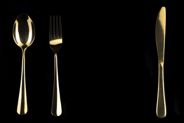 Golden knife and spoon on a black background. Cutlery