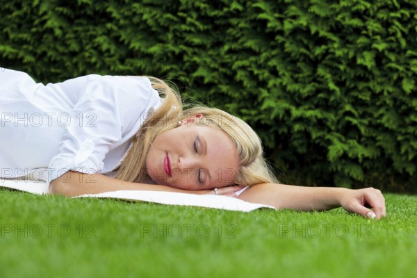 A young woman lies in the meadow to relax. Lunch break in the park. Austria