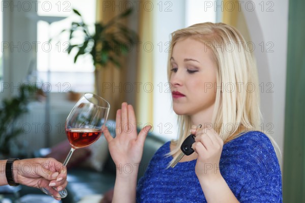 A young woman with car keys refuses a glass of wine. Don't drink and drive