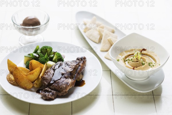Grilled steak meal with hummus dip starter on table