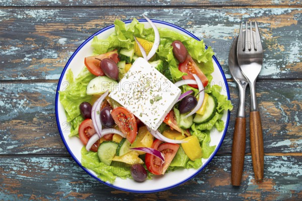 Traditional Greek Salad with Feta Cheese, Tomatoes, Bell Pepper, Cucumbers, Olives, Herbs in white ceramic bowl on blue rustic wooden table background from above, Cuisine of Greece, food photography, food photography