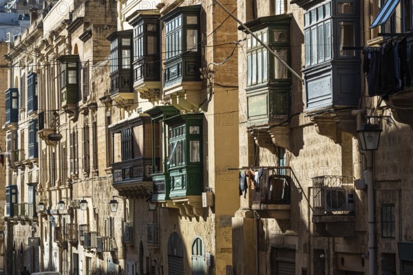 Valletta, Malta, 01 07 2022: Historical houses with wooden bow windows and terraces in a narrow street, Europe