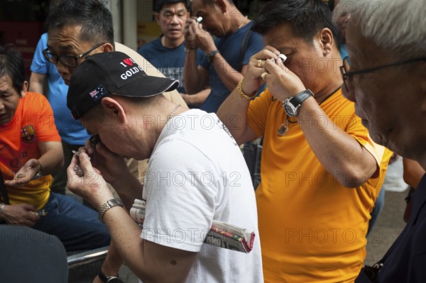 10.02.2018, Singapore, Republic of Singapore, Asia, Buyers and sellers inspect small pendants and amulets with Buddha figures at a flea market near the Buddha Tooth Relic Temple in Singapore's Chinatown district. The Buddha figures come from Thailand and can be very valuable depending on their age, quality and temple of origin. However, forgeries are also common, Asia