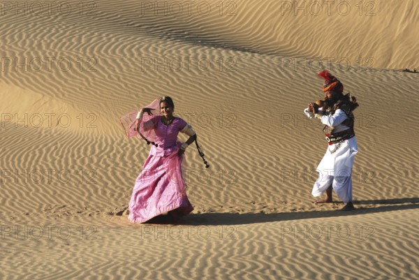 Rajasthani man playing been in front of woman in sand dune, Rajasthan, India MR#704C, 704D