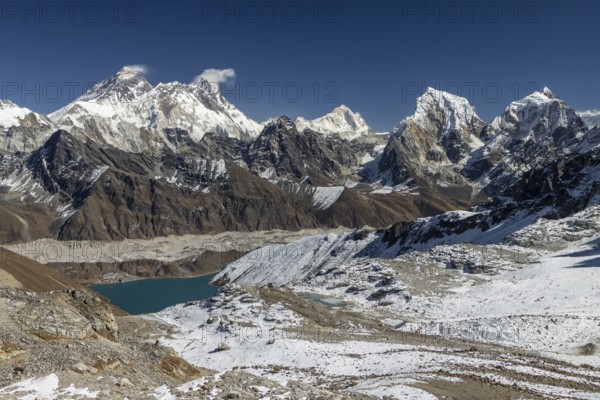 View from Renjo La, the mountain pass in Khumbu, the Everest Region, photographed on a clear, blue sky, autumn day. Mountain panorama consists of eight-thousanders: Mount Everest, Lhotse, Makalu, and other Himalayan peaks: Nutptse, Cholatse, Taboche. Ngozumpa, the longest glacier in Himalayas is below. Gokyo settlement sits on its lateral moraine and the Gokyo Lake, Dudh Pokhari shore. Three Passes Trek, post-monsoon trekking season. Sagarmatha National Park, UNESCO World Heritage Site. Solukhumbu, Nepal, Asia