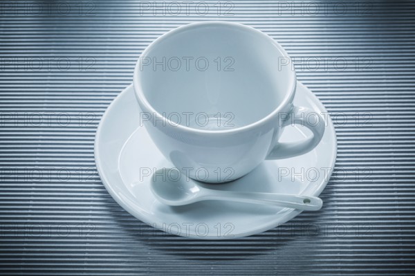 Coffee cup saucer teaspoon on striped background