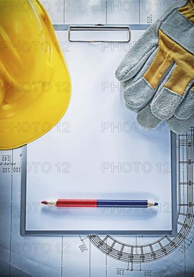 Clipboard pencil building helmet safety gloves on blueprint construction concept