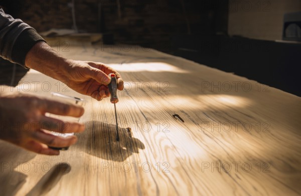 Person using tools on wood in a workshop with warm sunlight creating a focused and serene atmosphere