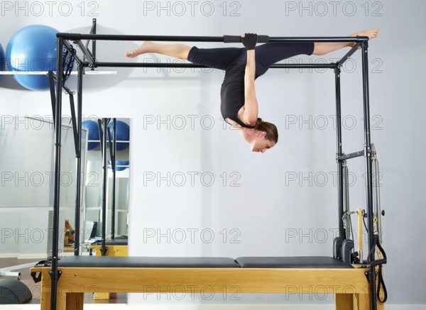 Pilates woman in cadillac walk over reformer upside down exercise at gym