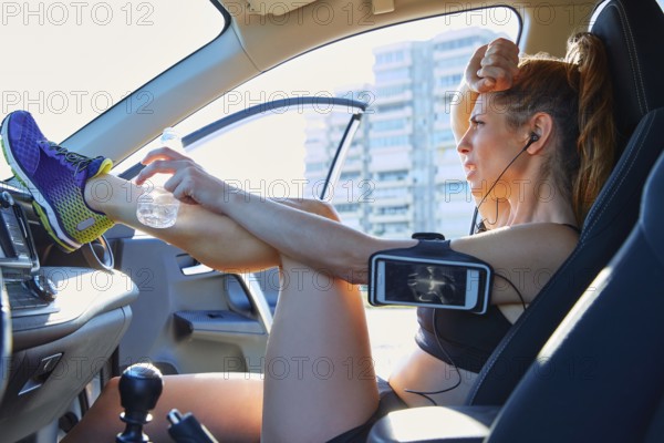 Runner woman relaxing after workout sitting inside a car