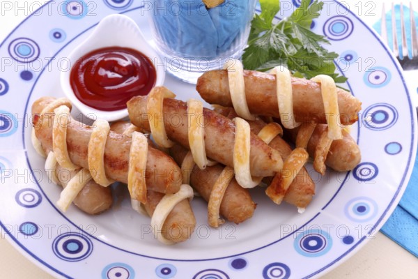Twisted pastry around chicken sausages with ketchup