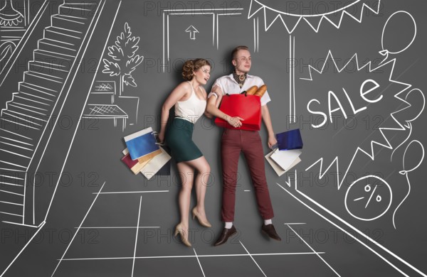 Love story concept of romantic couple shopping against chalk drawings background. Young happy couple standing together with shopping bags in a shopping centre during a sale